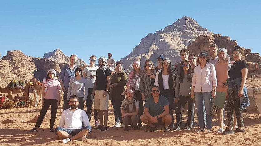 A group of Misbah Center students and tourists enjoying a trip in the desert of Wadi Rum, Jordan.