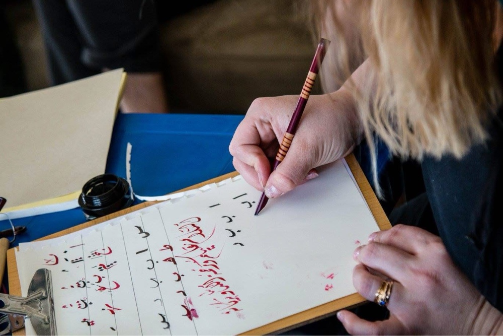 A student writing Arabic during a private lesson at Misbah Center